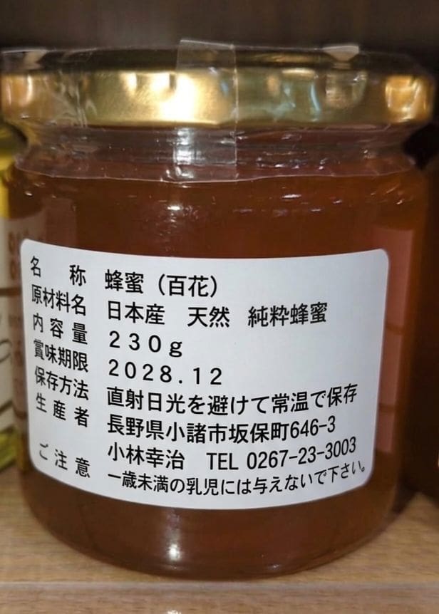 「浅間山麓・小諸高原産百花蜂蜜」の230g瓶3本セットです。各瓶には白いラベルが貼られており、製品情報、原産地（小諸高原を含む）、内容量、賞味期限、および保存方法が日本語で記載されています。この100％天然の百花蜂蜜は、その純粋な地域の風味と天然の品質で高く評価されています。.